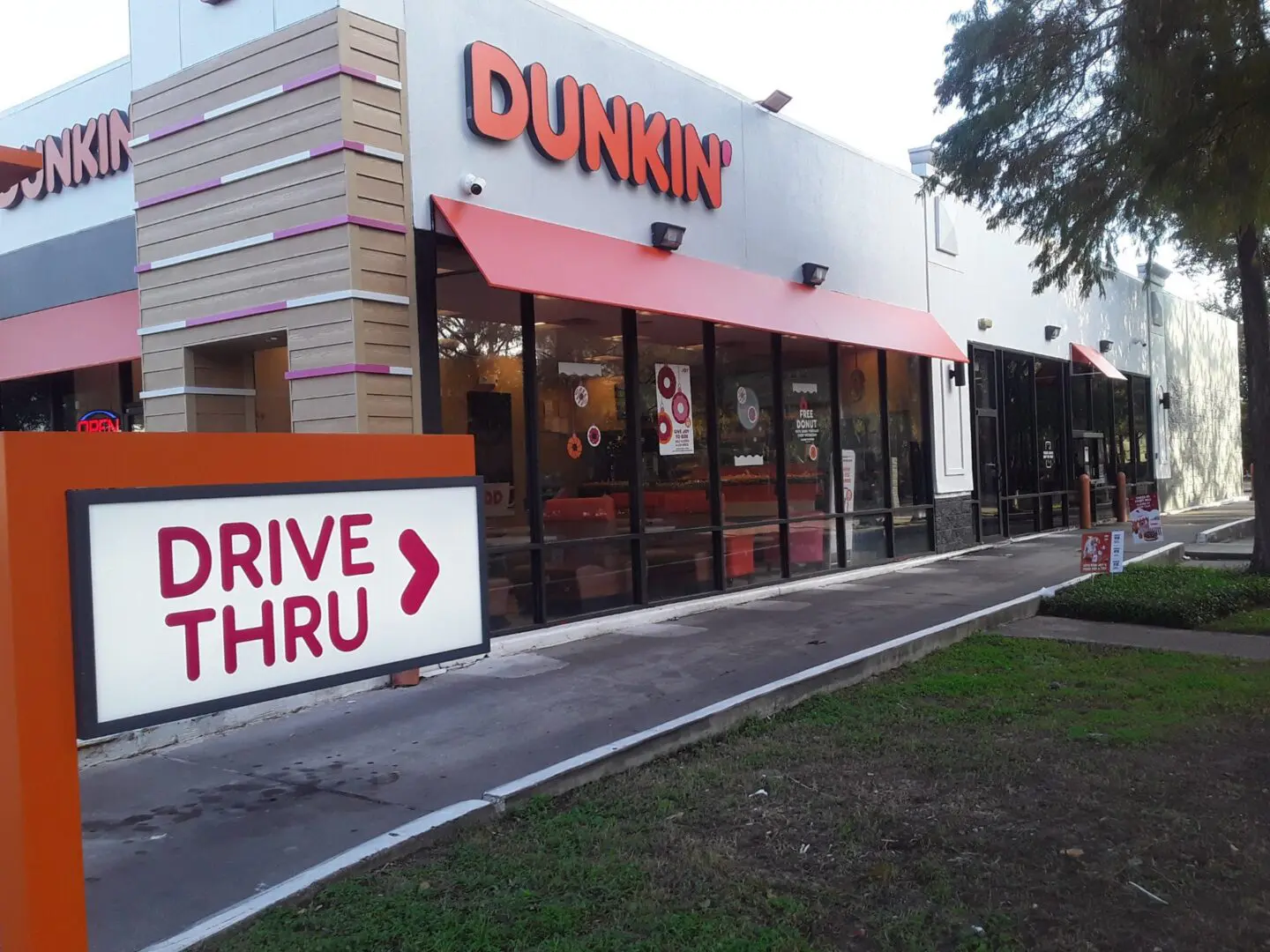 Dunkin' store with a drive-thru sign on a clear day.