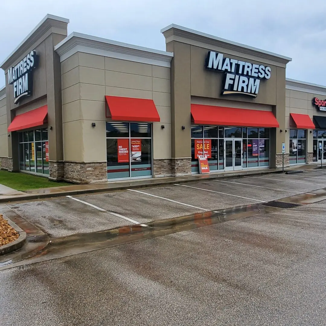 Exterior of a Mattress Firm store with red awnings on a rainy day.