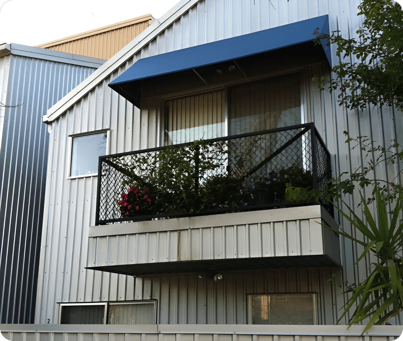 Balcony with plants and a blue awning on a modern building.