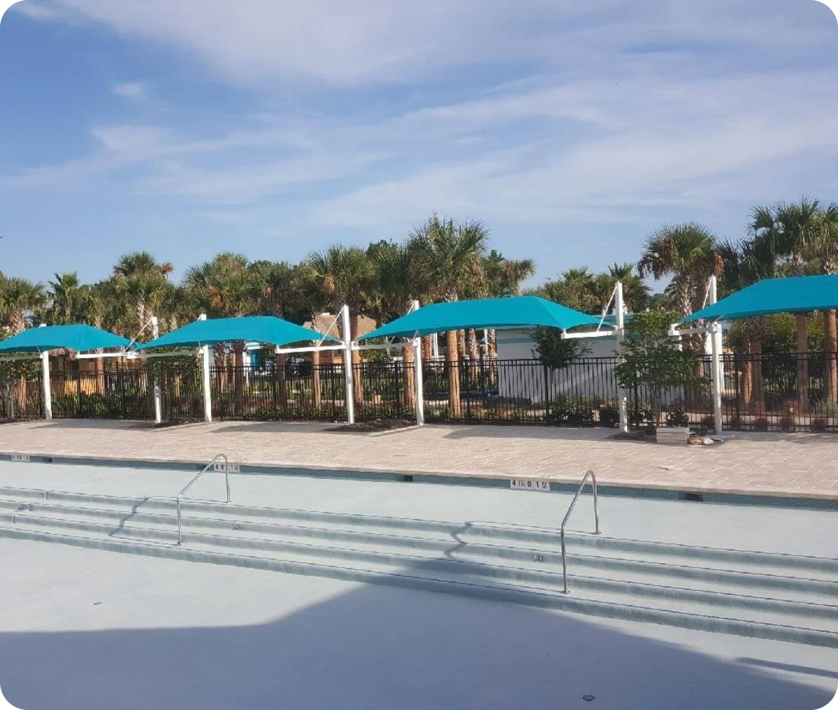 Sunlit pool deck under turquoise fabric canopies